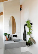  In the bathroom, industrial materials like steel and concrete are animated by plants, including orchids and aerophytes that thrive in the moist environment.
