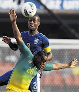 Brazil's Dede and South Africa's Benni McCarthy (front) fight for the ball during the international friendly soccer match in Sao Paulo on Friday Picture: PAULO WHITAKER/GALLO IMAGES