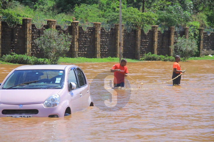 Rescuers try to remove a car that has been stuck in the rain water at Kenyatta University area on Wednesday, May 1, 2024.