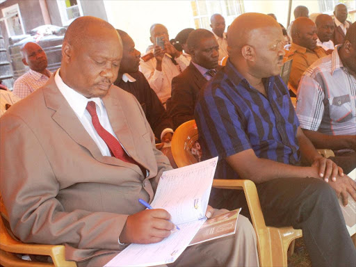 Busia Governor Sospeter Ojaamong signing condolence book during the burial of George Awori, 53, the nephew to former VP Moody Awori in Samia. He was flanked by Busia Assembly Speaker Bernard Wamalwa and Nangina MCA John Obwogo/ JANE CHEROTICH.