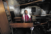 Archbishop Thabo Makgoba at a broken desk in a mud hut used as a classroom by the Samson Senior Primary School in Libode, Eastern Cape