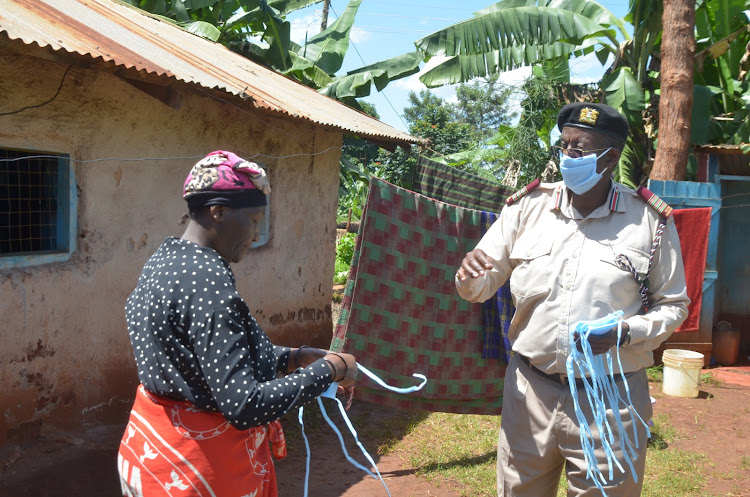 Murang'a county commissioner Mohamed Barre gives a face mask to a woman in Mjini slums on May 13, 2020