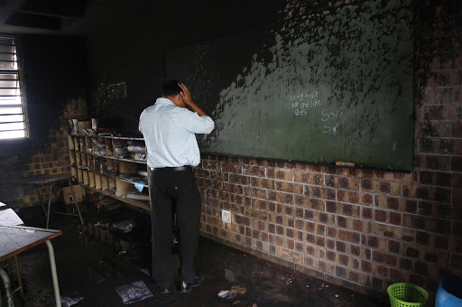 A teacher at Hill view Primary in Reservoir Hills looks at a burnt out classroom with the words " Things must not end like this. Sorry Sir" written on the charred blackboard. Two classrooms were burnt by Informal residents protesting against a councillor and poor service delivery.