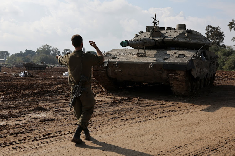 An Israeli soldier gestures towards a tank, amid the ongoing conflict between Israel and the Palestinian Islamist group Hamas, in southern Israel.
