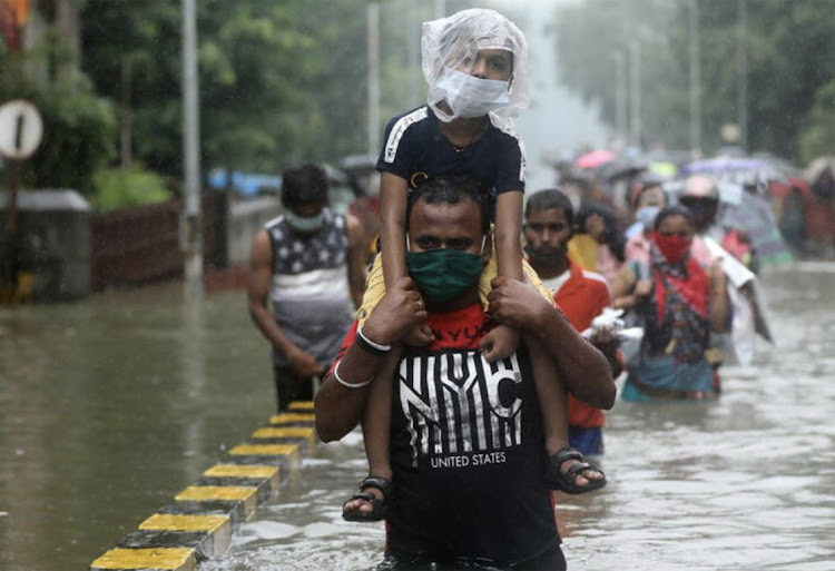 A man carries a child through a waterlogged road after heavy rainfall in Mumbai on September 23 2020. File Picture: FRANCIS MASCARENHAS/REUTERS