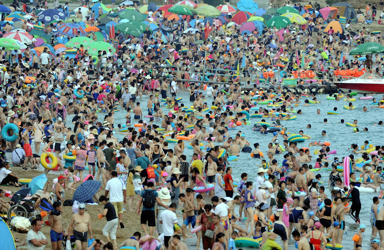 People enjoy themselves at a beach to beat the heat as the temperature reaches 32 degrees Celsius in Dalian, Liaoning Province of China.