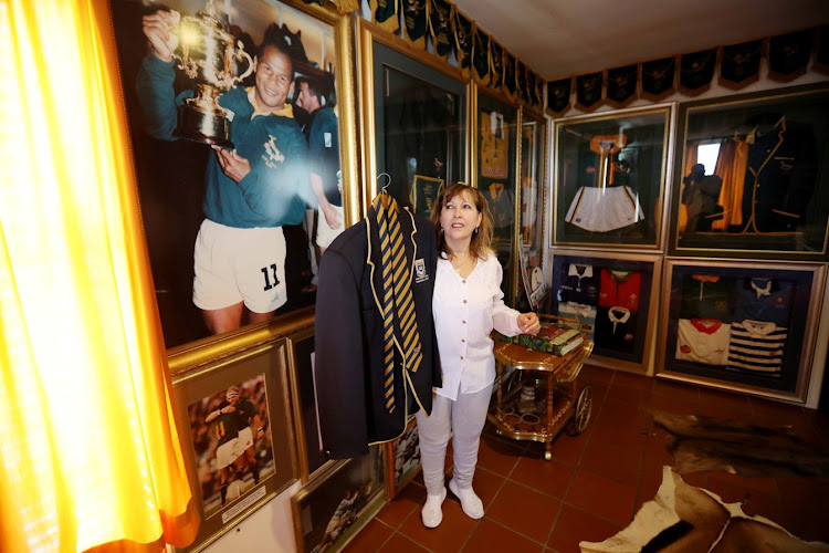 Maria Williams in a room at the family home filled with pictures, newspaper articles, rugby jerseys and accolades for her late husband.