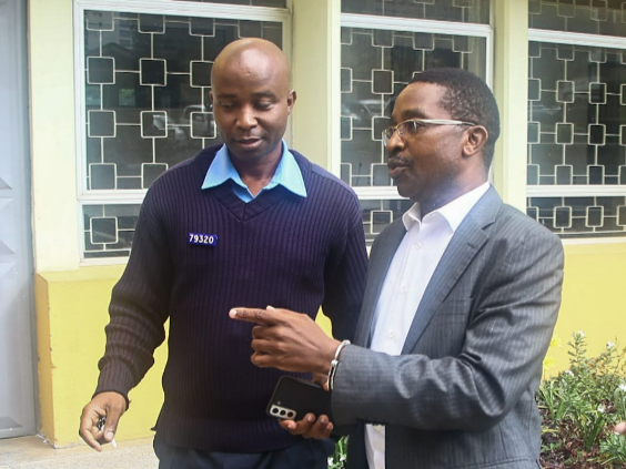 Former Murang'a Governor Mwangi wa Iria is escarted by a police officer at court precincts on Tuesday, April 30, 2024.