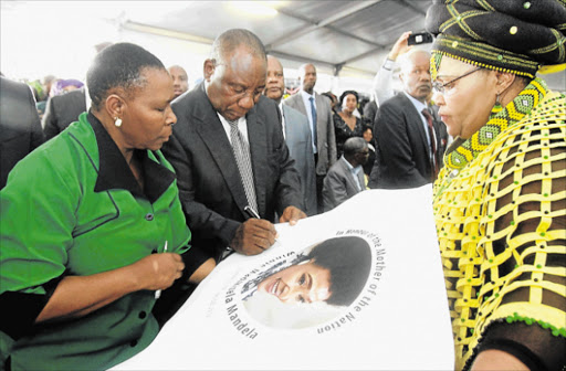 MOVING TRIBUTE: President Cyril Ramaphosa spoke emotionally yesterday at the memorial service of Winnie Madikizela-Mandela at Mphuthumi Mafumbatha Stadium in Mbizana. He signed a commemorative picture with provincial MPL Nonceba Kontsiwe, left, with sports, recreation, arts and culture MEC Pemmy Majodina looking on Picture: LULAMILE FENI