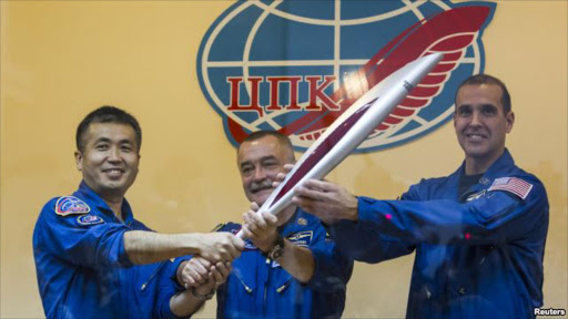 International Space Station (ISS) crew members, (L to R) Japanese astronaut Koichi Wakata, Russian cosmonaut Mikhail Tyurin and U.S. astronaut Rick Mastracchio, pose with the torch of the 2014 Sochi Winter Olympic Games, at the Baikonur cosmodrome, Nov. 6, 2013