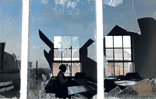 DEDICATED: A lone student carries on with her work though most of the classroom windows at Moses Mabhida Senior Secondary School were vandalised Picture: ALAN EASON
