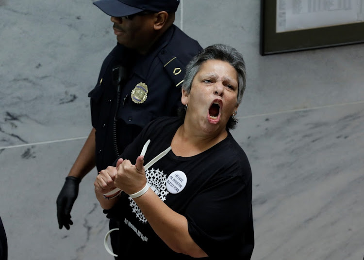 A protester is arrested during a demonstration against US President Donald Trump's Supreme Court nominee Brett Kavanaugh, and in support of Dr Christine Blasey Ford, who has accused Kavanaugh of sexual assault.