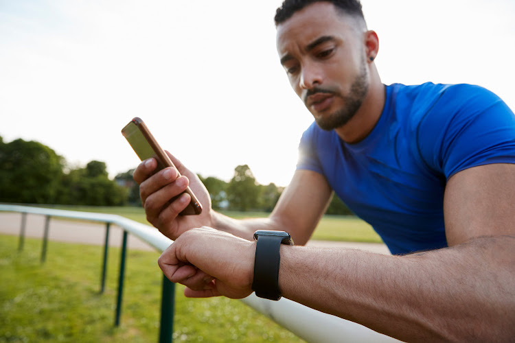 Athlete using fitness app on smartphone and smartwatch.