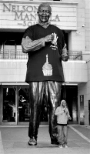 LARGER THAN LIFE: A concert on Nelson Mandela Square in Sandton will honour Madiba's birthday. His bust dwarfs Musa Mthombeni. Pic: Jennifer Wheatley. Circa 2009.
