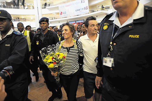 WARM WELCOME: Police surround Debbie Calitz and Bruno Pelizzari on their arrival at OR Tambo International Airport in Johannesburg on June 27 after their release by Somali pirates. Calitz was arrested on Friday after police allegedly found drugs in her Pretoria flat