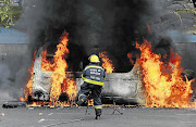 TURN UP THE HEAT: A fireman rushes to a minibus set alight by Cape Peninsula University of Technology protesters on the Cape Town campus yesterday