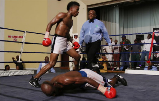 Xolani Mcotheli moves to the neutral corner after knocking down Flint Mdletshe as referee Lulama Mtya looks on during their vacant SA junior welterweighttitle fight held at the Orient theatre on sunday .PICTURE: Michael Pinyana ©DAILY DISPATCH