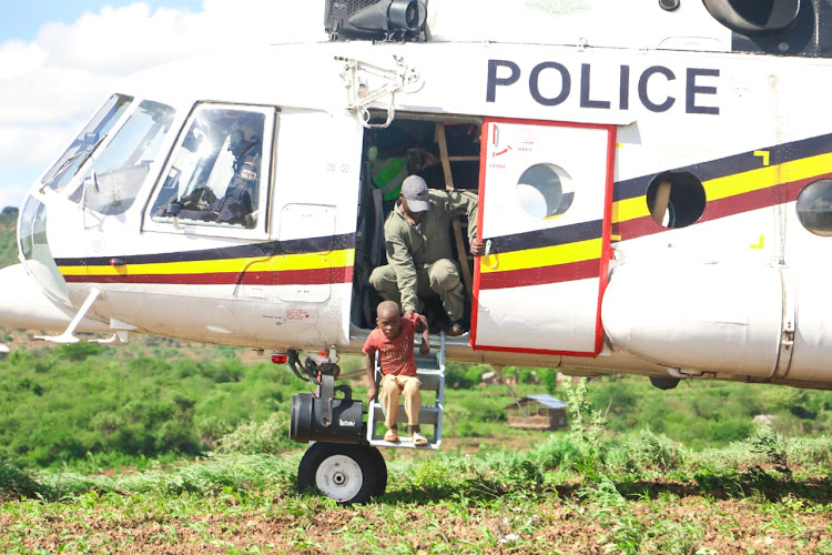The National Police Service (NPS) Airwing Officer helps a five-year-old Mutuku Kioko down a helicopter after he was marooned by floods at Nduani in Yatta, Machakos County on April 23, 2024.