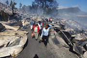 Helpless residents walking through the destroyed mountainside township of Mandela Park in Imizamo Yethu, Hout Bay. File photo