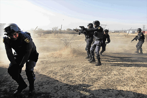 Police shoot at striking workers at the Lonmin mine in North West on August 16. A quiet state of emergency has been declared in the area Picture: KEVIN SUTHERLAND