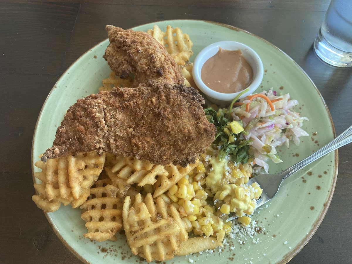 Chicken tenders with waffle fries, slaw, and corn salad