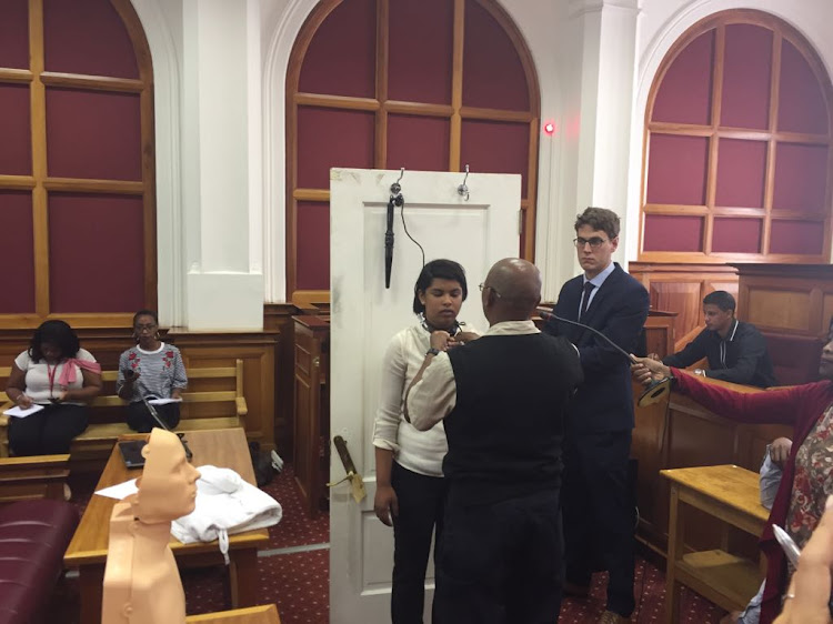 Spier maintenance man Desmond Daniels demonstrates in the High Court in Cape Town on Wednesday how he untied the cord of a hair iron from Susan Rohde's neck.