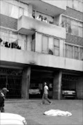 TRAGIC END: A man walks past the body of a woman on Olivia Street in Berea. She fell from the eight floor of her apartment building to escape a fire that was caused by an electrical fault. Pic. Vathiswa Ruselo. 06/10/08. © Sowetan.