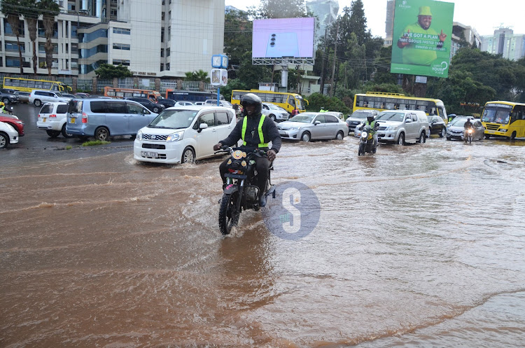 Motorists drive through flooded road after heavy downpour on April 24, 2024.