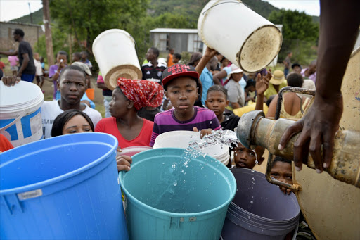 Damonsville residents queue for water on January 15, 2014 in Brits, South Africa. Government is investigating the cause of the water crisis in the Muthutlung area which led to the death of three people.