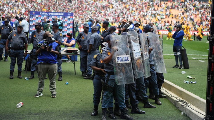 Police form a protective barrier as Kaizer Chiefs fans hurl missiles after the DStv Premiership Soweto derby against Orlando Pirates at FNB Stadium on Saturday.