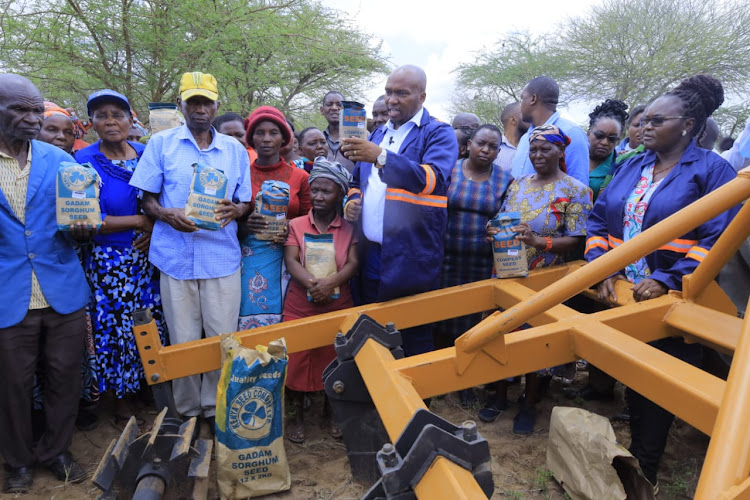 Kitui CEC Stephen Kimwele and farmers show off packets of drought tolerant crop seeds at Kyeng'e on Wednesday during the launch of the ripping programme.