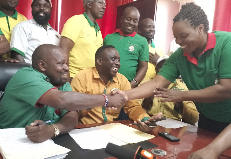 Bomet KNUT Executive Secretary Desmond Langat (left) with his KUPPET counterpart Paul Kimeto (centre) greet a KNUT official during a press conference in Bomet town on Monday.