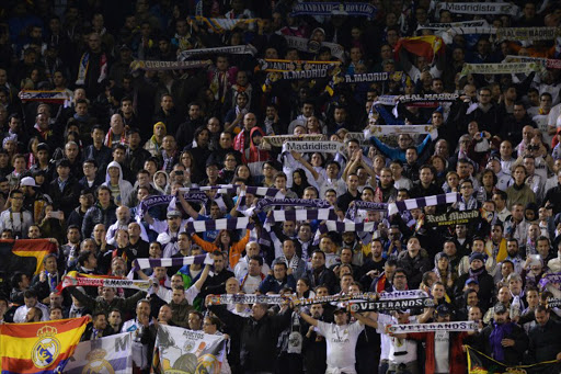 Real Madrid fans hold up their scarves in the crowd during the UEFA Champions League, group B, football match between Liverpool and Real Madrid at Anfield in Liverpool, northwest England, on October 22, 2014. Madrid will propose to their disciplinary board that 17 fans have their season tickets revoked after they were identified as being responsible for instigating derogatory chants aimed at Lionel Messi and FC Barcelona during a clash with Celta de Vigo on 7 December 2014. PAUL ELLIS / AFP