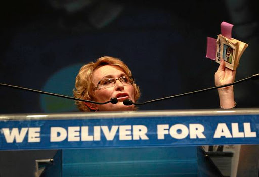 Premier Helen Zille holds up a copy of the South African constitution during a public address.