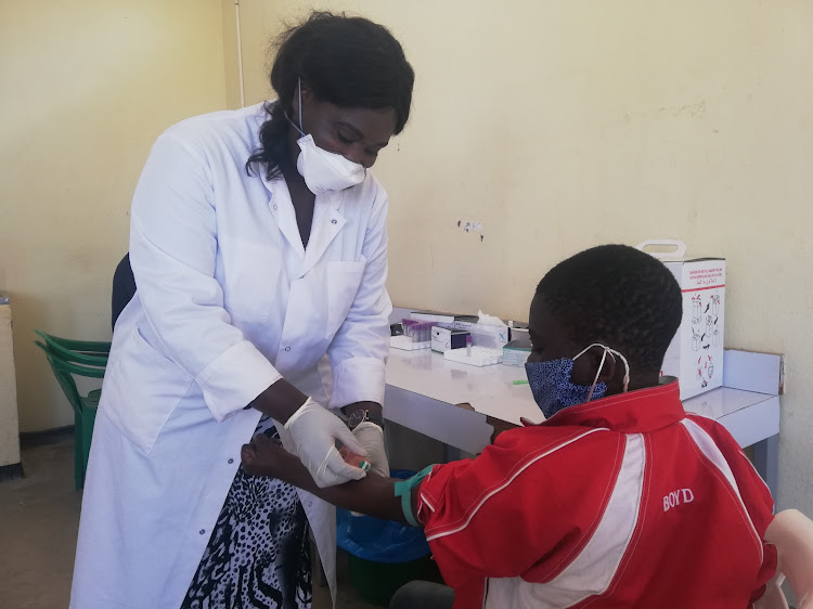 A 13-year-old Malawian boy, Saidi, has his blood drawn by lab technician Tambu Dzai at a rural clinic in Chiradzulu district outside Blantyre.