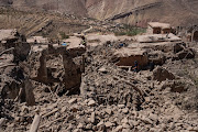 People walk past collapsed buildings on September 11, 2023 in Douzrou, Morocco. More than 2,000 people are now believed to be dead following an earthquake measuring 6.8 on the Richter scale that struck villages in the High Atlas mountains around 70km south of Marrakesh on September 8.
