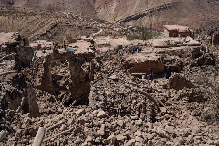 People walk past collapsed buildings on September 11, 2023 in Douzrou, Morocco. More than 2,000 people are now believed to be dead following an earthquake measuring 6.8 on the Richter scale that struck villages in the High Atlas mountains around 70km south of Marrakesh on September 8.