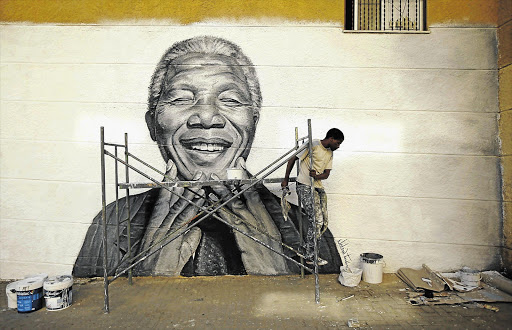 Nelson Tavares, 24, works on a mural of Nelson Mandela in his neighbourhood in Lisbon, Portugal. Mandela was yesterday discharged from hospital after almost three months of being treated for a lung infection.