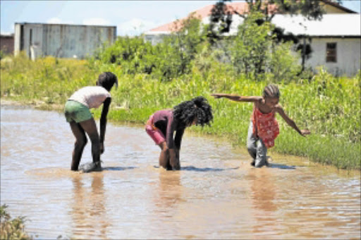 EXTREME WEATHER: A group of children play in a flooded section of the road leading to the Fort Grey Clinic. PHOTO: MARK ANDREWS