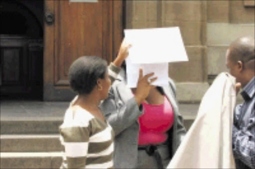FACELESS: A friend hides Nompumelelo Ntshiza's face after her ex-husband Victor Akpanta Usen's case was postponed yesterday. 04/12/08. Pic. Bafana Mahlangu. © Sowetan.