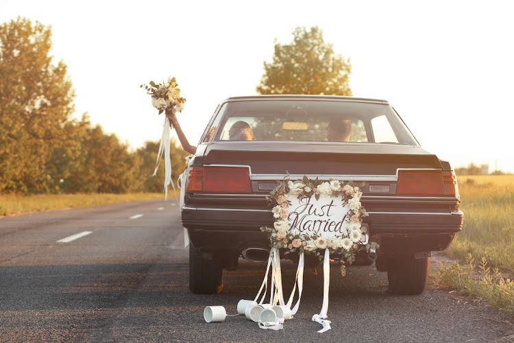 Happy wedding couple in decorated car PIC: 123RF