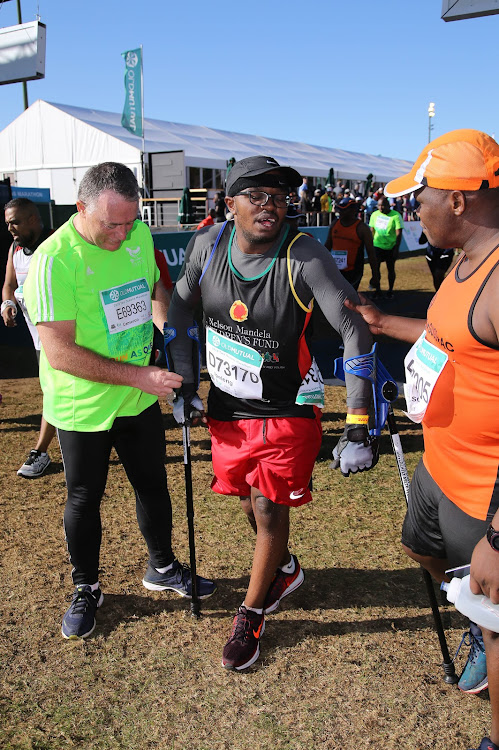 Ipeleng Khunou, the first person to finis the race on crutches, with Cameron Dugmore during the 2018 Old Mutual Two Oceans Marathon 21km Half Marathon starting at SA Breweries and finishing at UCT Rugby Fields on March 31, 2018 in Cape Town, South Africa.
