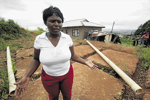 Hlengiwe Msweli next to the site on which the eThekwini municipality wants to build a low-cost house for her in Inanda, outside Durban. Behind her is her home, which she fears will be demolished by the municipality to make way for an access road Picture: THULI DLAMINI