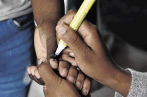 A voter gets his thumbnail marked with indelible ink at a voting station in Marikana, North West. The writer is perturbed by the conditions of some of the voters' fingers.