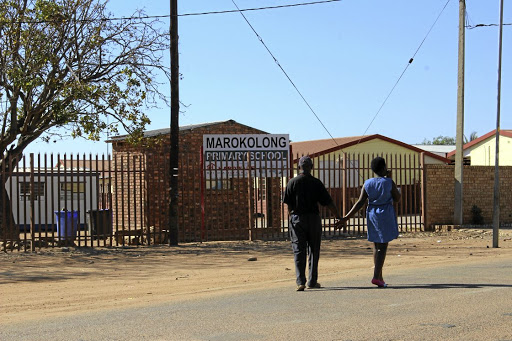 A Grade 7 who got infected from using filthy toilets at Marokolong Primary School in Hammanskraal, north of Pretoria, walks past the school with her father.