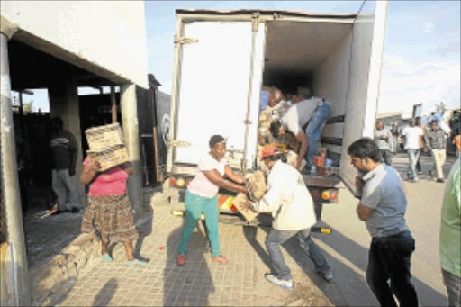 SALVAGE MISSION: Foreign shop owners load their wares in a truck as they leave Diepsloot following the violence that erupted after the fatal shooting of two men in the area. Police monitored the tense situationPHOTO: VELI NHLAPO