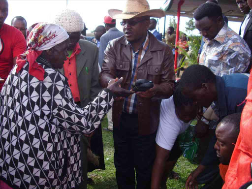 1.Left,partly hidden,Ndaragwa MP, Waweru Nderitu and Kiriita MCA,Maina Nderitu join dancers during Mandaraka day celebrations held at Ndaragwa stadium on wednesday.The MCA advised Nyandarua Governor and his Deputy to reconcile and work together,or they will lose the County leadership to strangers. 2.Nyandarua County Speaker,Wahome Ndegwa,in a hat,and Kiriita MCA,Maina Nderitu,distribute shoes to Mau Mau war veterans during Mandaraka Day celebrations held at Ndaragwa stadium on Wednesday.Nderitu said the County top leadership should hold hands and work like the Mau Mau heroes did during the struggle for independence.