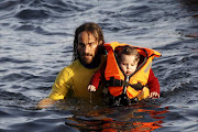 A volunteer lifeguard rescues a baby after a catamaran carrying about 150 refugees , most of them Syrian, sank of the Greek island of Lesbos on Friday. The death toll from drownings has mounted recently as the weather in the Aegan has taken a turn for the worse.