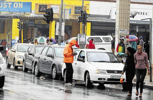 PAY UP: A parking warden in orange jackets employed by a company hired by the KSD Municipality in Mthatha, checks on vehicles parked on Owen, Sutherland and York Roads in the town. Plans by the municipality to introduce a fee-based system parking system are falling flat because there are not enough marshalsThe municipality Mthatha as there is a shortage of parking space in the town