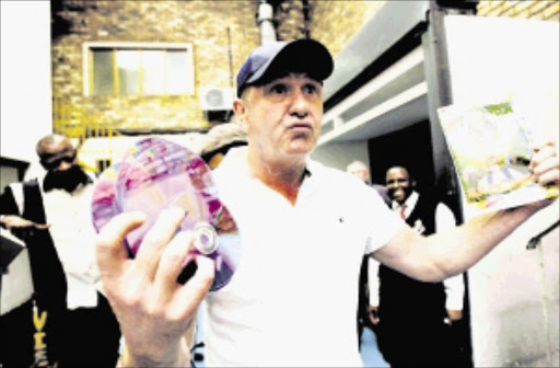 Filmmaker and comedian Leon Schuster poses with fake DVDs of one of his films on Thursday, 19 February 2009. Pirated DVDs worth R25 million were destroyed at a venue in Midrand. Schuster, a long time anti-piracy advocate, attended the destruction of the goods confiscated by the SA Revenue Service' special investigations unit.These DVDs feature film made locally and internationally and are being sold on city streets costing South Africa's film industry millions of rands a year. Pic: Werner Beukes. © SAPA